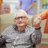 A member of the Recreation and Well-Being team holding hands with a  male resident